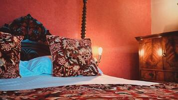 Una habitación con una cama, cabecera de madera y pared roja.