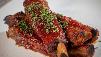 Un plato de costillas a la parrilla adornado con hierbas picadas.