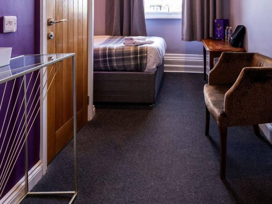 A hotel room with a bed, a desk, a chair, a TV, and a window with curtains.