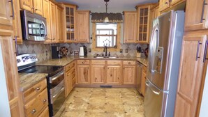 A kitchen with wooden cabinets, a stainless steel refrigerator, and a microwave. - Mountain Views, 2 Peaceful Acres, Game Rm, hispeed WiFi, A/C, Comfy Beds 3279 (Estes Park)