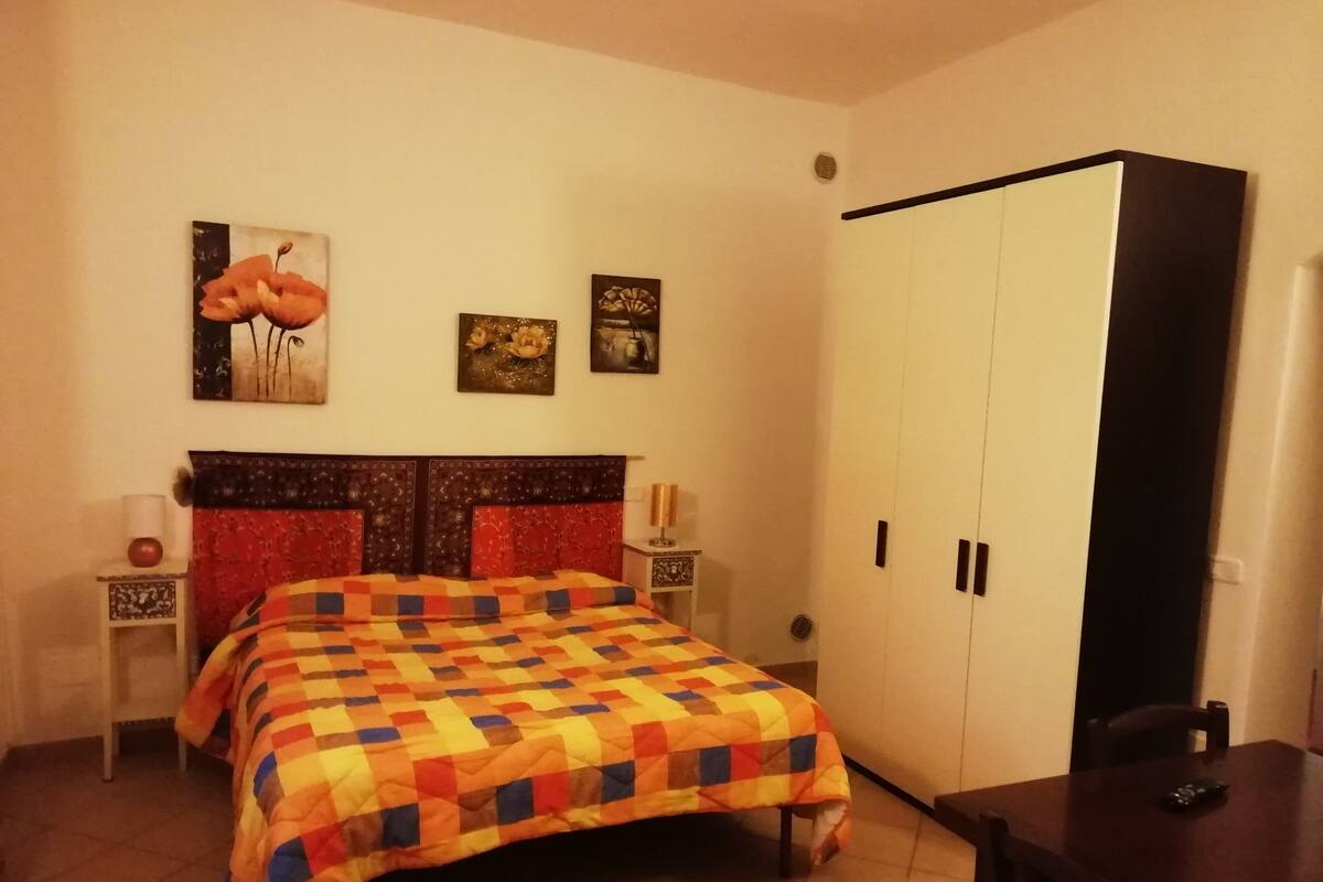 Un dormitorio con una cama, un armario y una mesita de noche con lámpara.