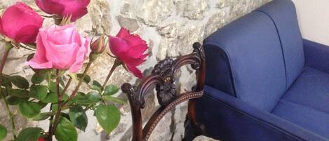 A stone wall, a blue sofa, and pink roses.