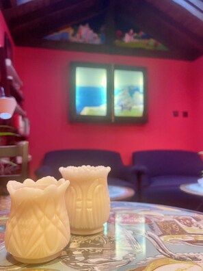 Una habitación con pared roja, un sofá y dos jarrones decorativos sobre una mesa.