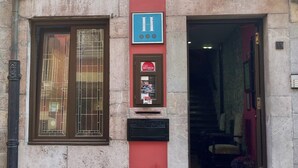 Un edificio de fachada roja, una ventana con reja de metal y un cartel de servicio Michelin.