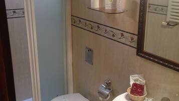 Un baño con inodoro, bidé, lavamanos, toallero y espejo.