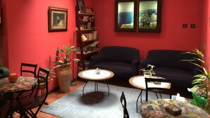 Una sala de estar acogedora con paredes rojas, una estantería, dos sofás y un comedor con sillas y una mesa.