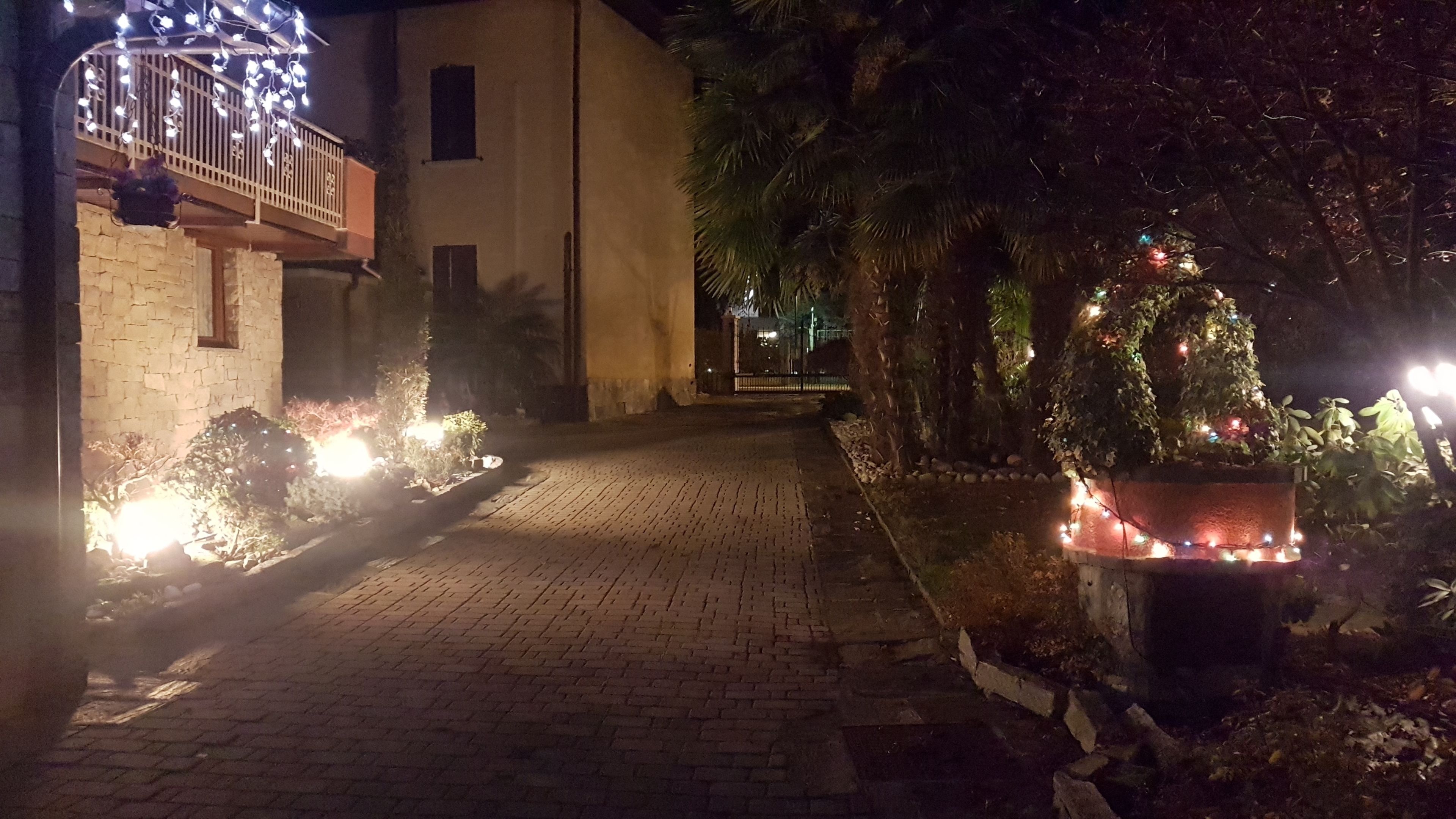 Un vialetto lastricato che conduce a un edificio con un balcone decorato con luci a stringa.