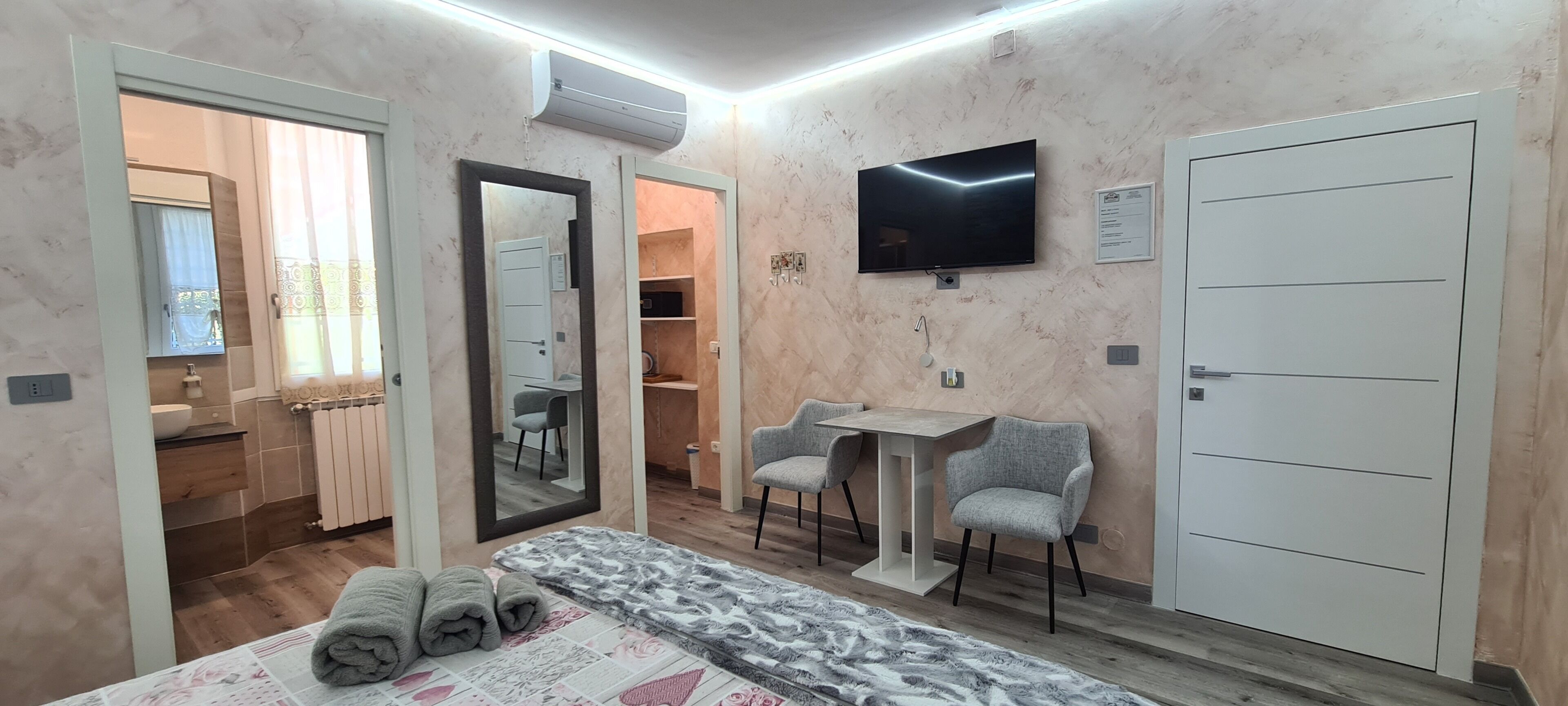 A bedroom with a bed, a desk, two chairs, a TV, and a wardrobe.