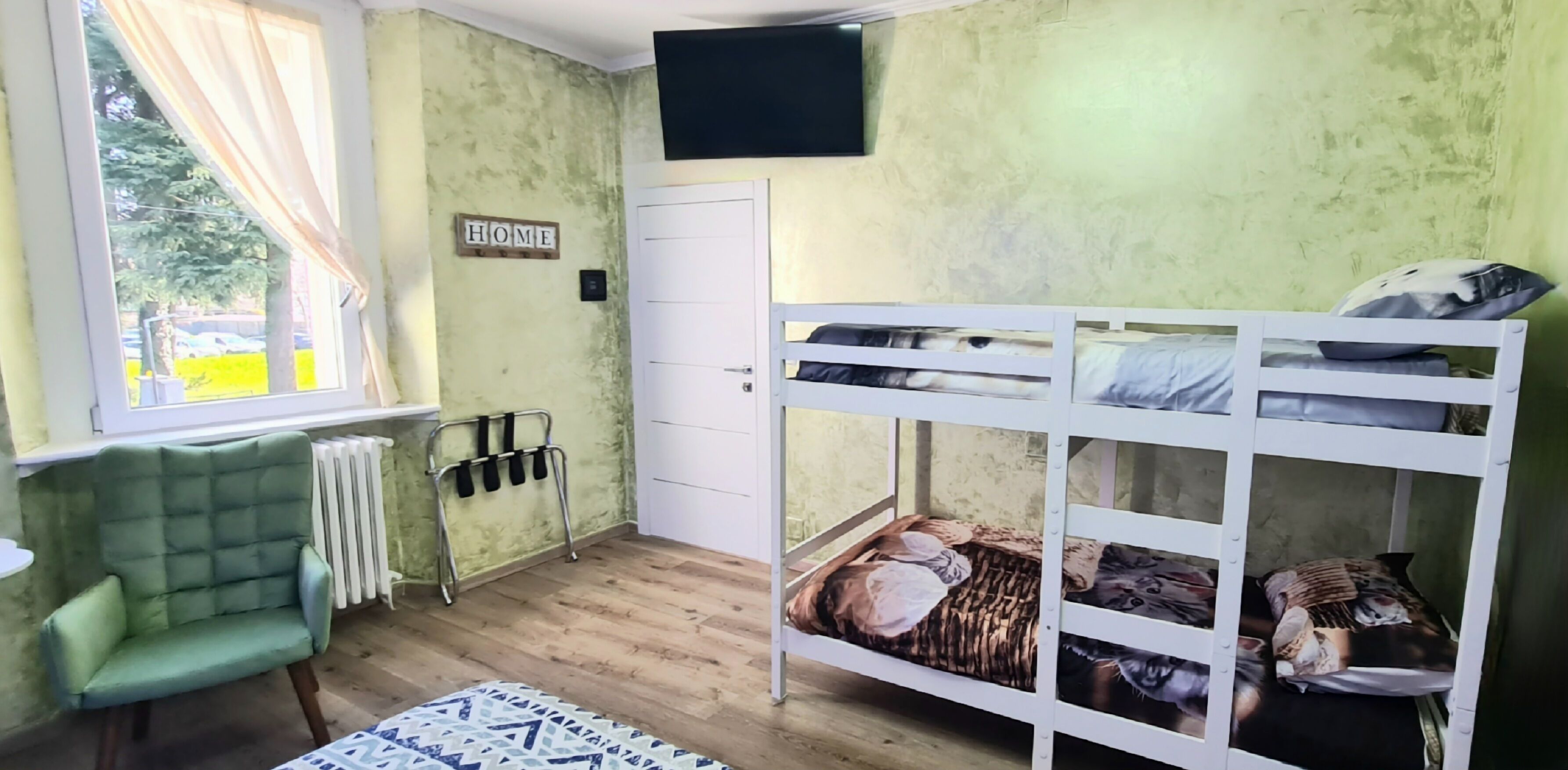 A room with bunk beds, a radiator, a green sofa, a window with curtains, and a 'HOME' sign.
