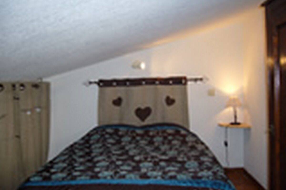 Un dormitorio con cama, lámpara de noche y armario.