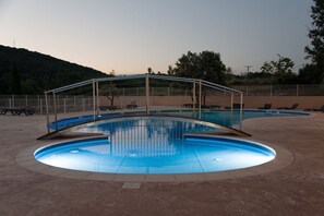 Una piscina con zona cubierta y sillas de descanso.