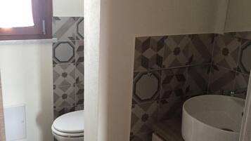 A small bathroom with a toilet, sink, and a window.