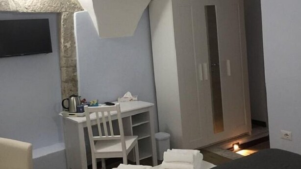 Ein kleines, modernes Schlafzimmer mit Bett, Schreibtisch und Kleiderschrank.