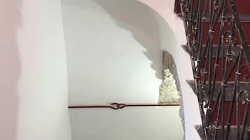 Una escalera con barandilla de metal negro y pared blanca con textura.