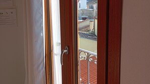 Ein Zimmer mit einem raumhohen Holzbalkon und Blick auf bunte Häuser.