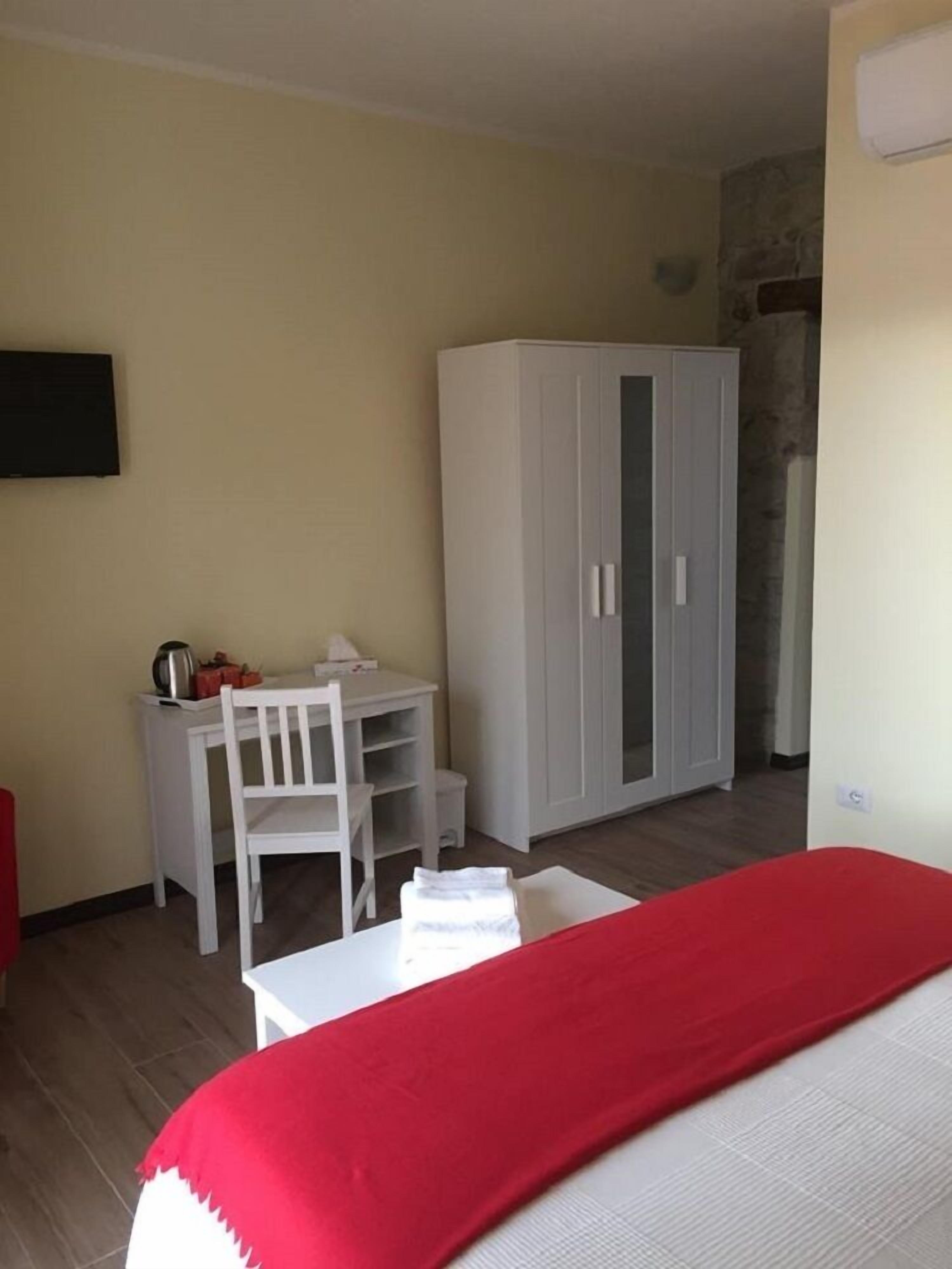Ein Zimmer mit Bett, Schreibtisch mit Stuhl, Kleiderschrank und Fernseher an der Wand.