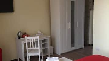 Une chambre avec un lit, un bureau et une chaise, une armoire et un téléviseur fixé au mur.