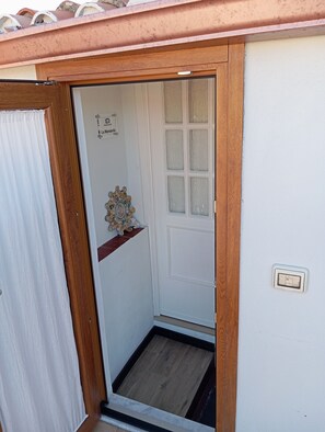 Une porte blanche avec un cadre en bois, une petite étagÚre ornée de quelques objets décoratifs et une enseigne au-dessus de la porte.