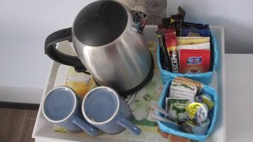 A tray with a silver mug, two blue cups, and a blue container holding food items and condiments.