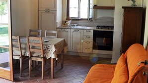 A compact kitchen with a dining table, chairs, and a sofa. - Agriturismo Fossederi (Santa Luce)