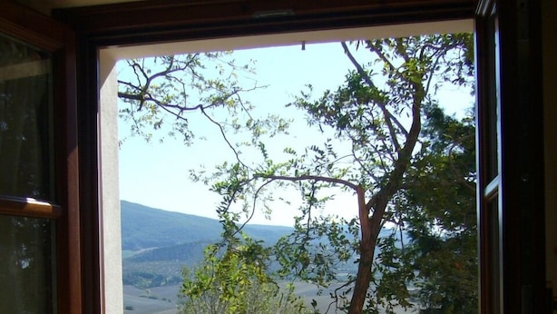 A window with a view of a landscape, including trees and hills. - Agriturismo Fossederi (Santa Luce)