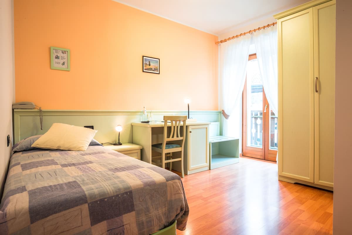A bedroom with a bed, a desk, a chair, and a wardrobe.