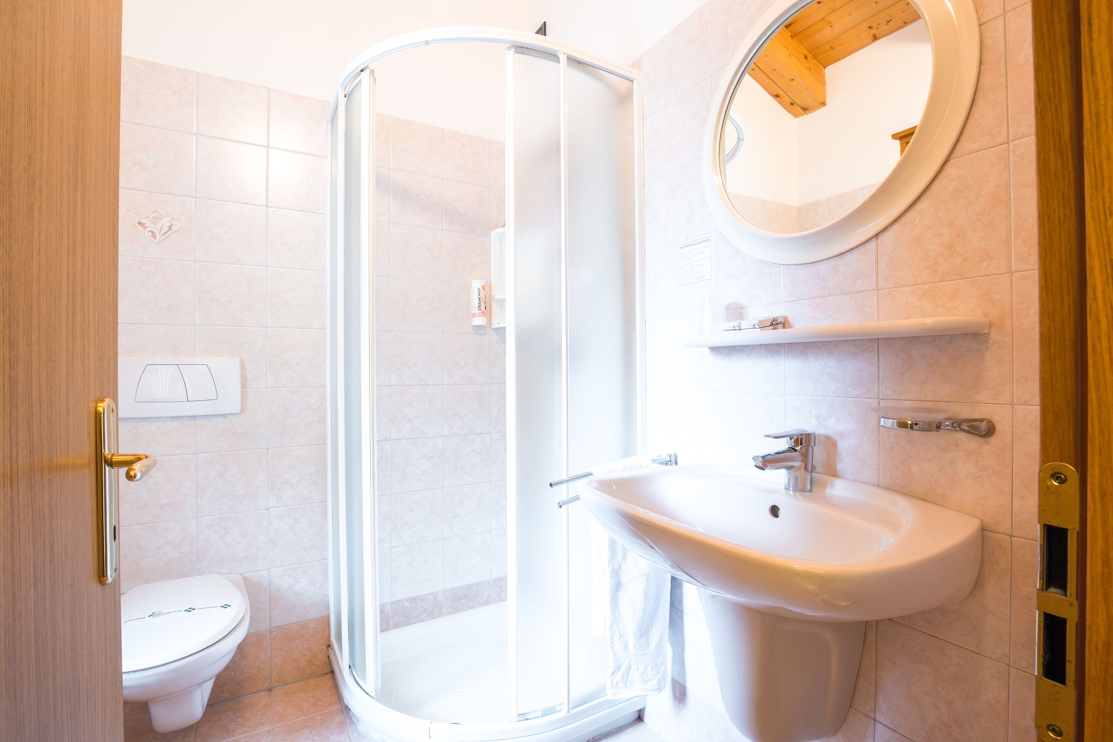 A bathroom with a shower, toilet, sink, and mirror.