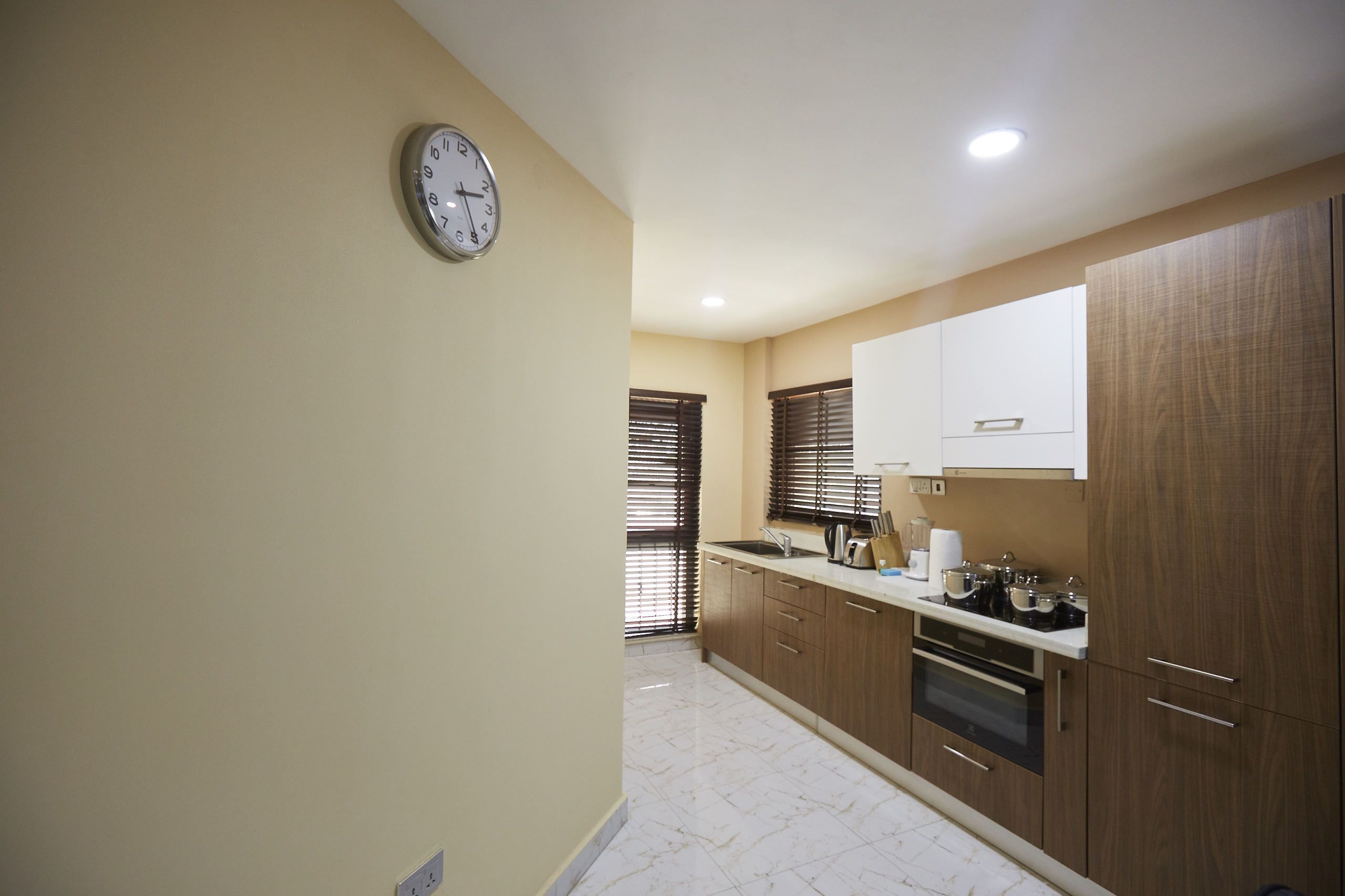 A kitchen with wooden cabinets, a sink, and a clock on the wall.