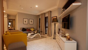 A modern living room with a sofa, armchairs, a coffee table, and a TV mounted on the wall. - Belanova Apartments & Suites (Abuja)