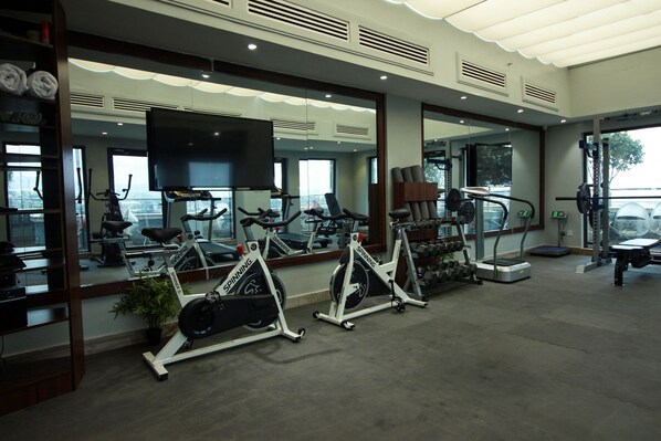 Un gimnasio con bicicletas estáticas, cinta de correr y equipo de levantamiento de pesas.