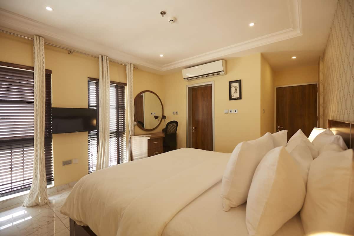 Une chambre à coucher avec un grand lit, une table de chevet, un miroir, un appareil de climatisation et une armoire.