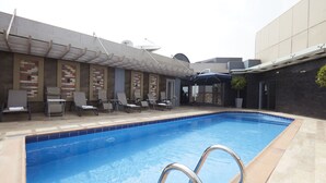 A swimming pool with lounge chairs and a covered seating area. - Belanova Apartments & Suites (Abuja)