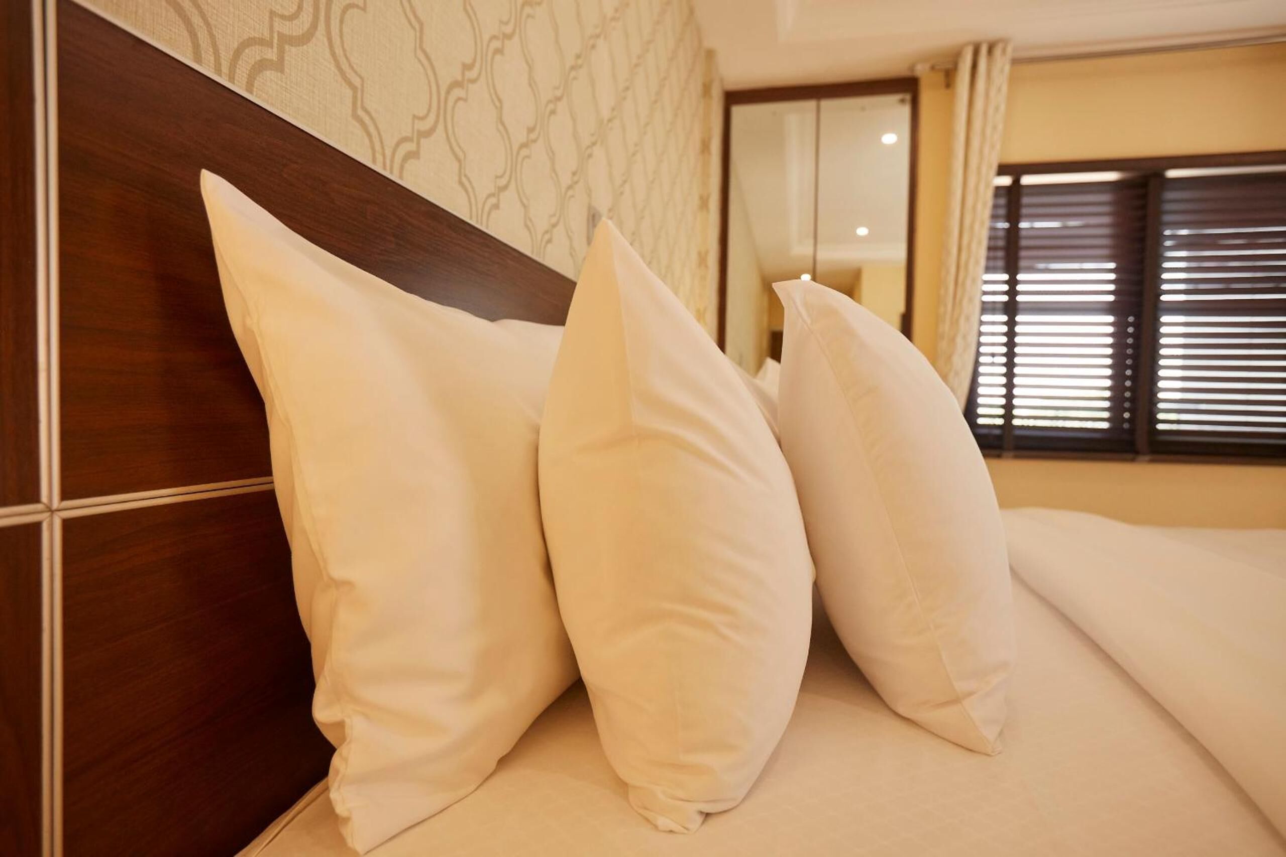A neatly made bed with white pillows and a wooden headboard in a hotel room.