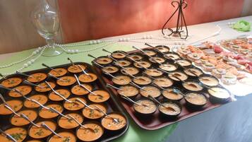 Una mesa de buffet con diversos alimentos, incluyendo una bandeja de sopa y varios recipientes pequeños con diferentes salsas.