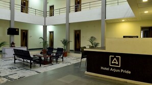 A hotel lobby with a reception desk, seating area, and a high ceiling with skylights. - Arjun Pride Hotel (Baramati)