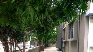 A paved walkway with trees on one side and a building on the other. - Arjun Pride Hotel (Baramati)