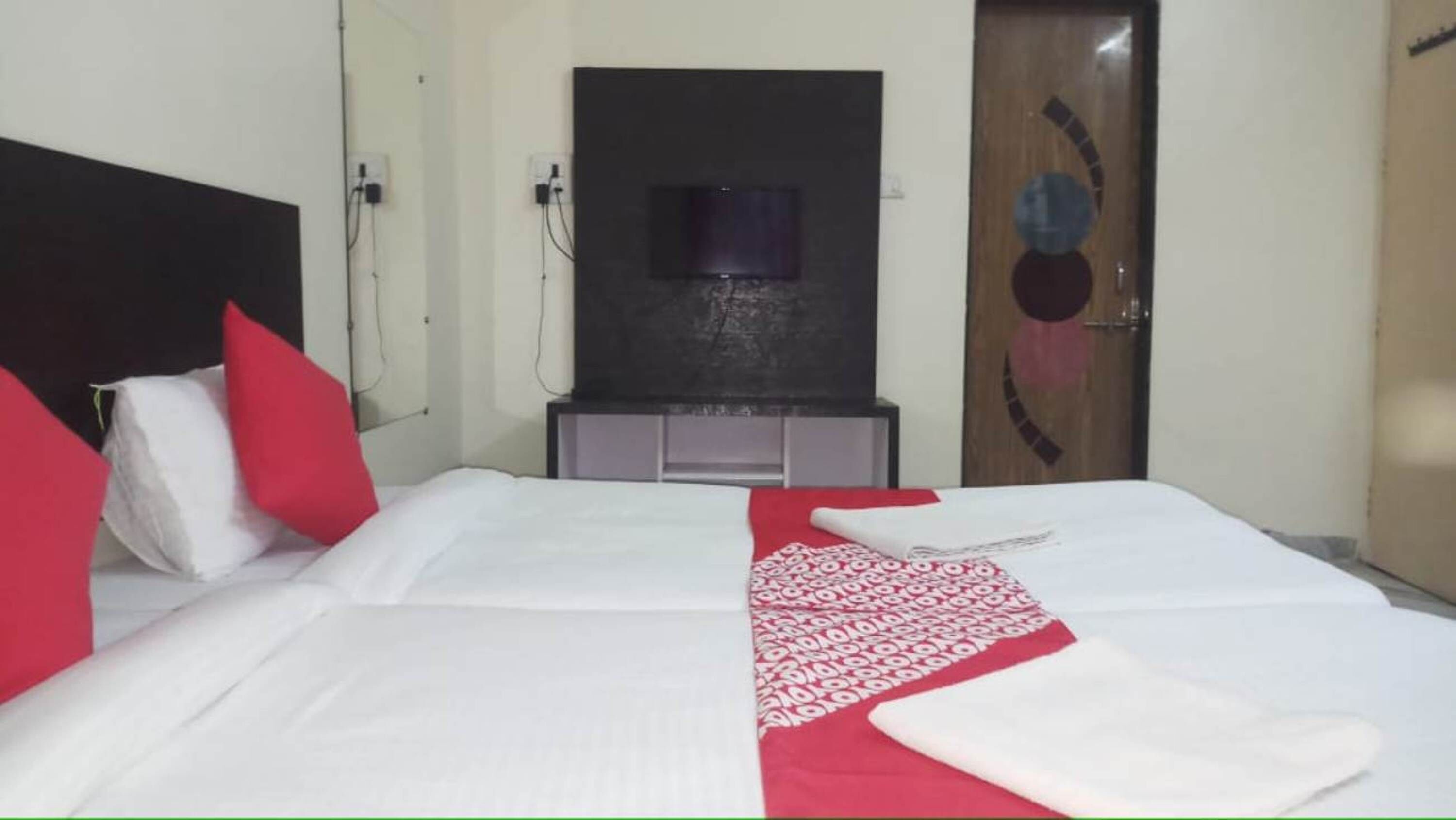 Une chambre d’hôtel avec un lit, une télévision et une porte ornée d’un motif circulaire.