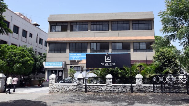 A building with a sign for 'Arjun Pride' and a sign for 'The Business Hotel'. - Arjun Pride Hotel (Baramati)
