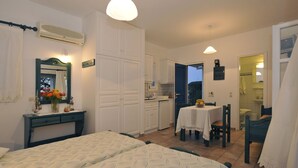 A bedroom with a bed, a desk, and a chair. There is a small table with a chair and a window. - Golden Sand Paros (Paros)
