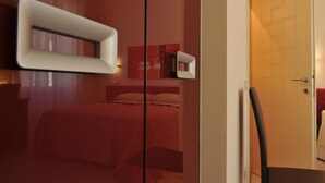 Una habitación de hotel moderna con una cama, una mesita de noche, una silla y una puerta.