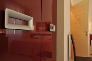 Una habitación de hotel moderna con una cama, una mesita de noche, una silla y una puerta.