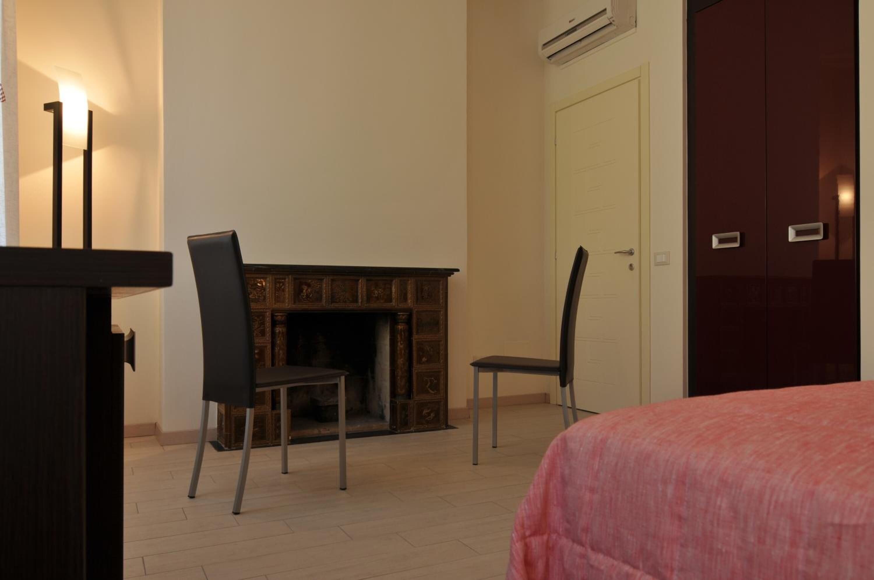 Un dormitorio con cama, chimenea, dos sillones y un armario.