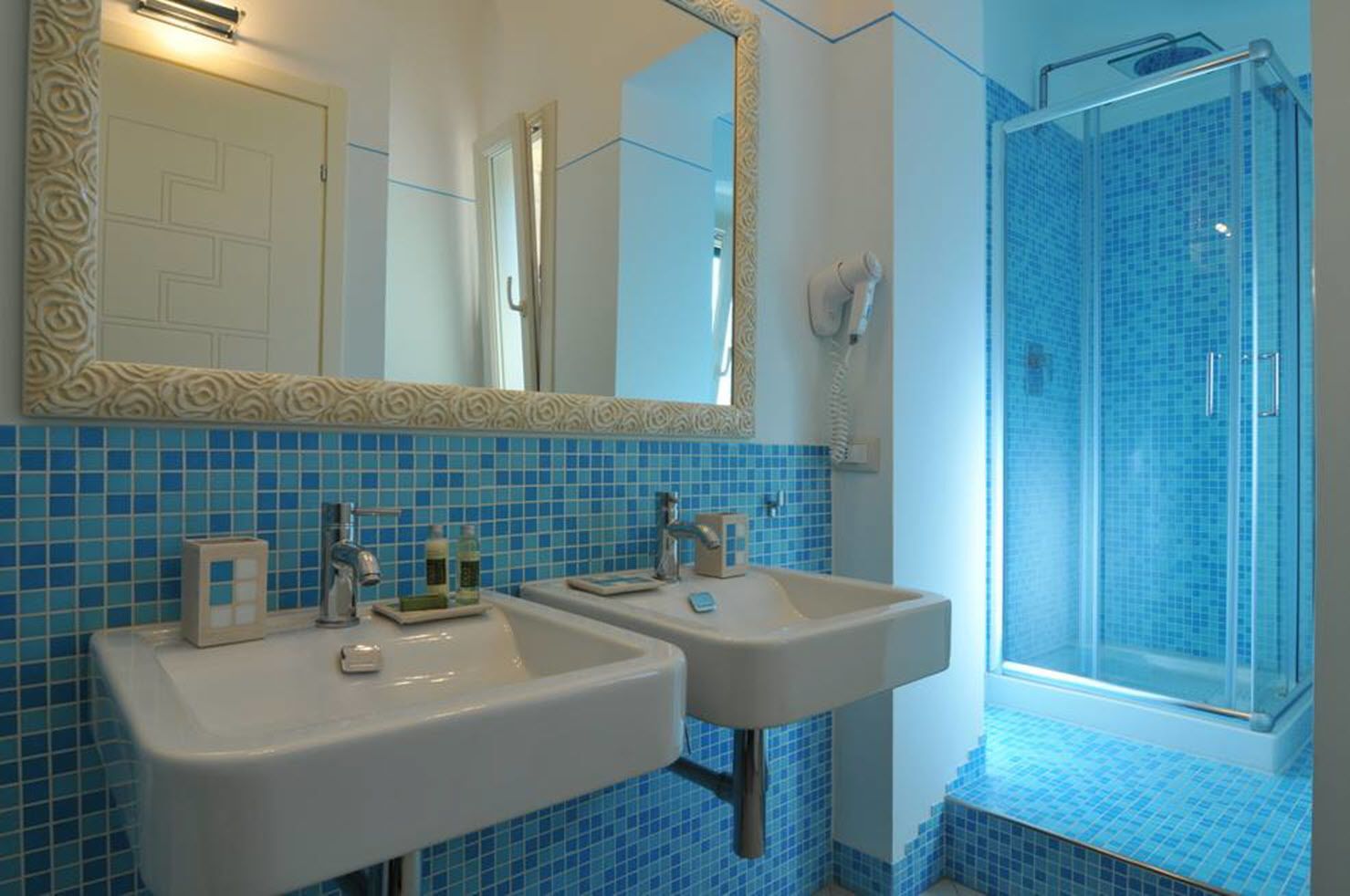 A bathroom with two sinks, a shower, and a large mirror.
