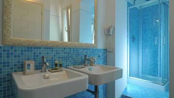 A bathroom with two sinks, a shower, and a large mirror.