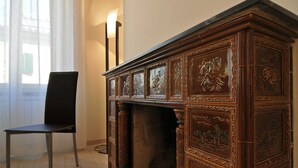 Un aparador de madera con tallas intrincadas, una silla negra y una lámpara.