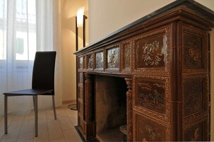 Un aparador de madera con tallas intrincadas, una silla negra y una lámpara.