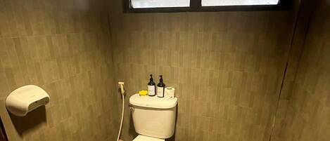 Une petite salle de bain équipée de toilettes, d’un sèche-mains et d’une poubelle.