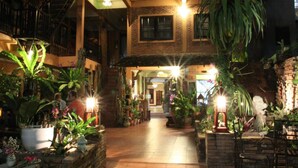 Un jardín interior con plantas en macetas y un sendero de ladrillo que conduce a la entrada de un edificio.