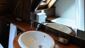 Interior em madeira com claraboia, duas pias e um espelho.