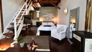 A bedroom with a bed, white armchair, and a wooden staircase. - Culinary Boutique Hotel Kladi Elias (Pangaio)